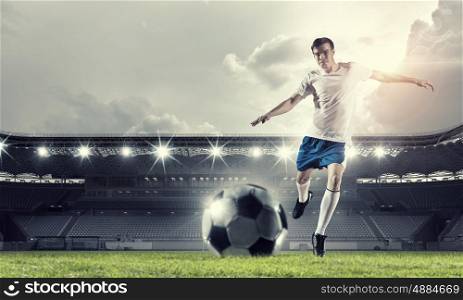 Soccer forward player . Determined football player at stadium hitting ball