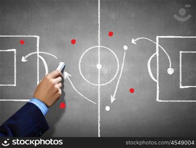 Soccer game strategy. Close up image of human hand drawing football tactic plan