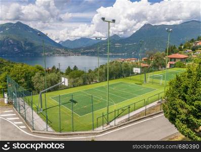 Soccer or football and basketball field on a background of mountains. Captured at Lake Como, Italy. Soccer or football and basketball field on a background of mountains