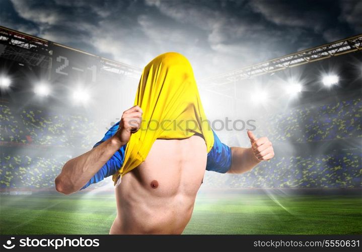 soccer or football player is celebrating goal on stadium with his jersey on head. celebrating a goal