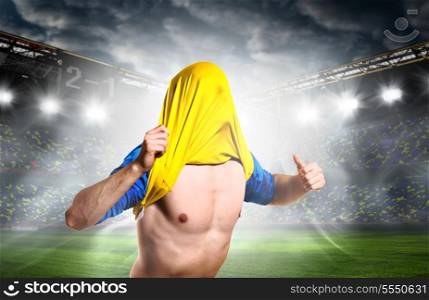 soccer or football player is celebrating goal on stadium with his jersey on head. celebrating a goal