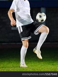 soccer player doing kick with ball on football stadium field isolated on black background in night