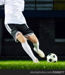 soccer player doing kick with ball on football stadium field isolated on black background in night