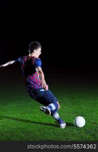 soccer player doing kick with ball on football stadium field isolated on black background in night
