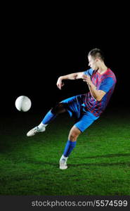 soccer player doing kick with ball on football stadium field isolated on black background in night