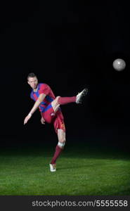 soccer player doing kick with ball on football stadium field isolated on black background