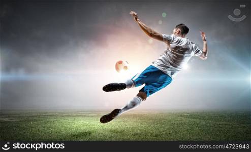 Soccer player hitting ball. Football player with ball in action at stadium