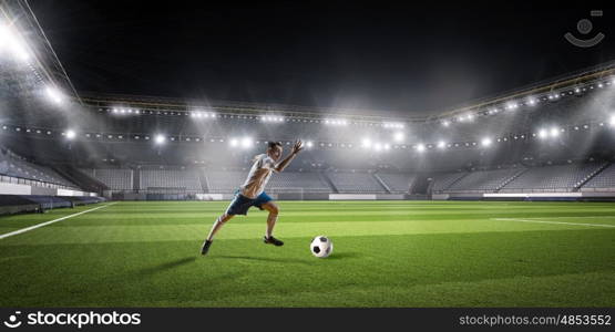 Soccer player hitting ball. Football player with ball in action at stadium