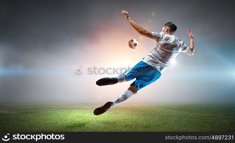 Soccer player hitting ball. Football player with ball in action at stadium