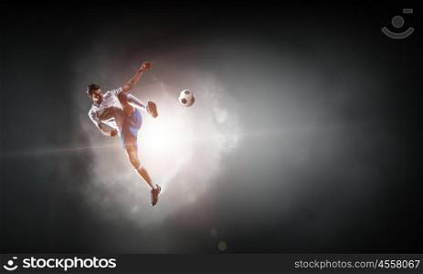 Soccer player hitting ball. Football player with ball in action outdoors