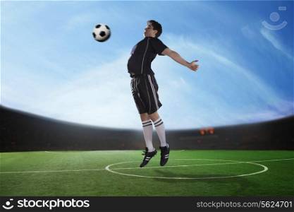 Soccer player hitting the ball with his chest in the stadium, day time