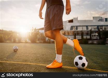 Soccer player with ball on the field at sunrise. Footballer on outdoor stadium, workout before game, football training