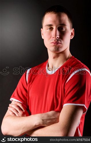soccer player with folded hands on dark background
