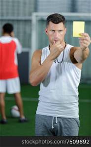 soccer referee showing yellow card to players during game