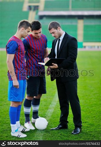 soccer sport manager in business suit coach and football player on stadium with green grass and white ball