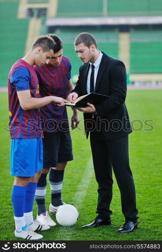 soccer sport manager in business suit coach and football player on stadium with green grass and white ball