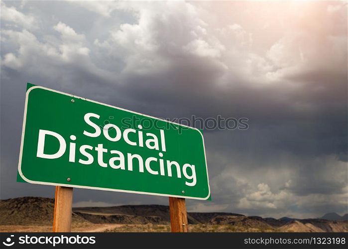 Social Distancing Green Road Sign Against Ominous Stormy Cloudy Sky.