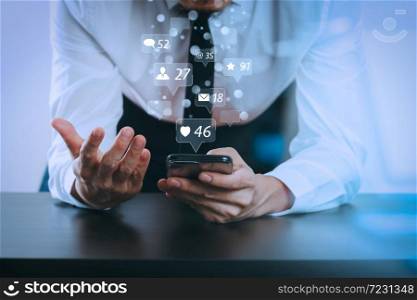 Social media and Marketing virtual icons screen concept.close up of businessman working with smart phone on wooden desk in modern office with glass reflected view