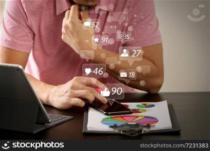 Social media and Marketing virtual icons screen concept.businessman in pink t-shirt working with smart phone and digitl tablet computer and document on wooden desk in modern office