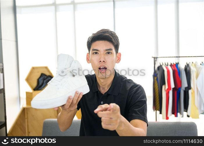 Social media influencer reviewing fashion shoe. Smiling young man vlogging about men&rsquo;s sports shoe and filming himself at home on a video camera.