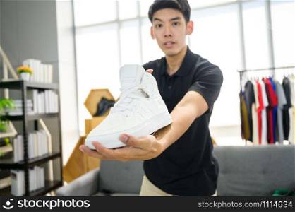 Social media influencer reviewing fashion shoe. Smiling young man vlogging about men&rsquo;s sports shoe and filming himself at home on a video camera.