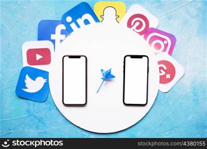 social mobile application icons around circular white frame with two cellphone against blue backdrop