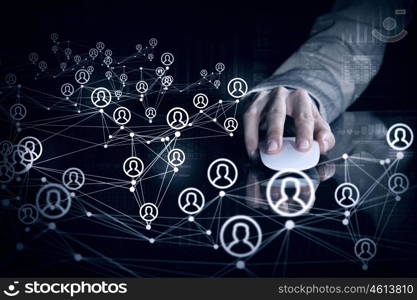 Social networking concept. Close up view businessman hand using computer mouse on reflective black surface and networking concept on dark background