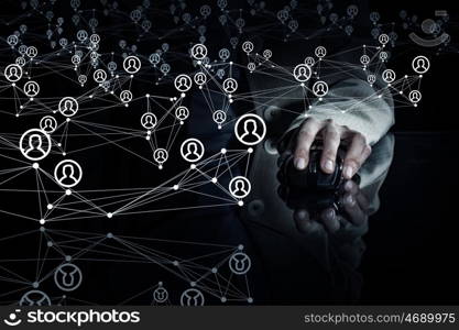 Social networking concept. Close up view businessman hand using computer mouse on reflective black surface and networking concept on dark background