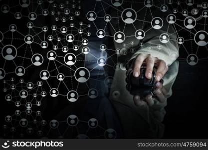 Social networking concept. Close up view businessman hand using computer mouse on reflective black surface and networking concept on dark background