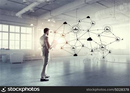 Social networking technologies. Businessman in office interior and social net connection 3D illustration