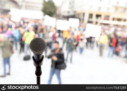 Social protest or public demonstration. Microphone in focus against unrecognizable crowd of people.