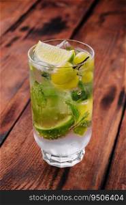 Soda water with grapes, ice and lime on wooden table