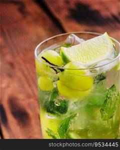 Soda water with grapes, ice and lime on wooden table