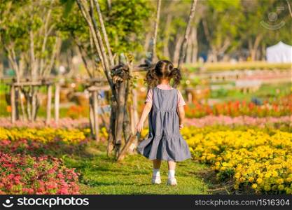 Soft blur of back of little girl run into flower garden with morning light.