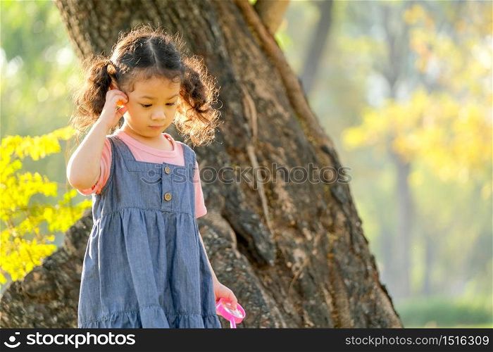 Soft blur of morning light shine to little girl hair and she walk with curious face in the park.
