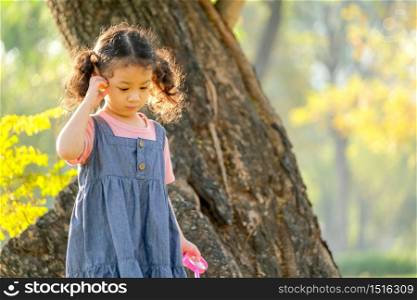 Soft blur of morning light shine to little girl hair and she walk with curious face in the park.