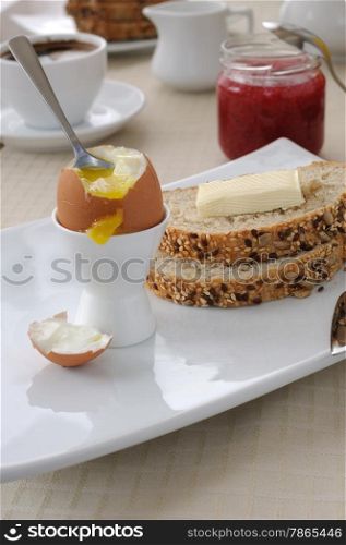 Soft-boiled egg with slices of oatmeal bread with butter for breakfast