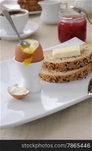 Soft-boiled egg with slices of oatmeal bread with butter for breakfast