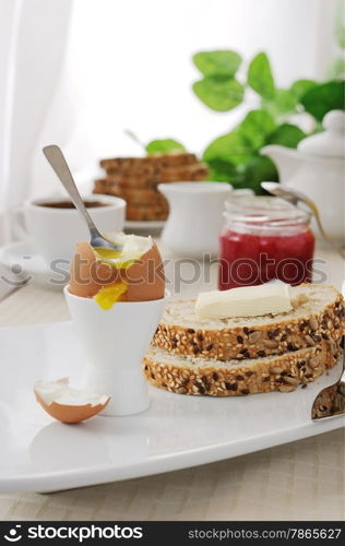 Soft-boiled egg with slices of oatmeal bread with butter for breakfast