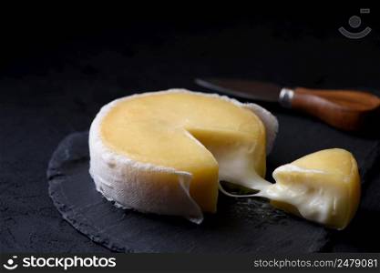 Soft cheese on a slate with cheese knife on background