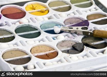 Soft earth tone chalks in their container with clip tool.