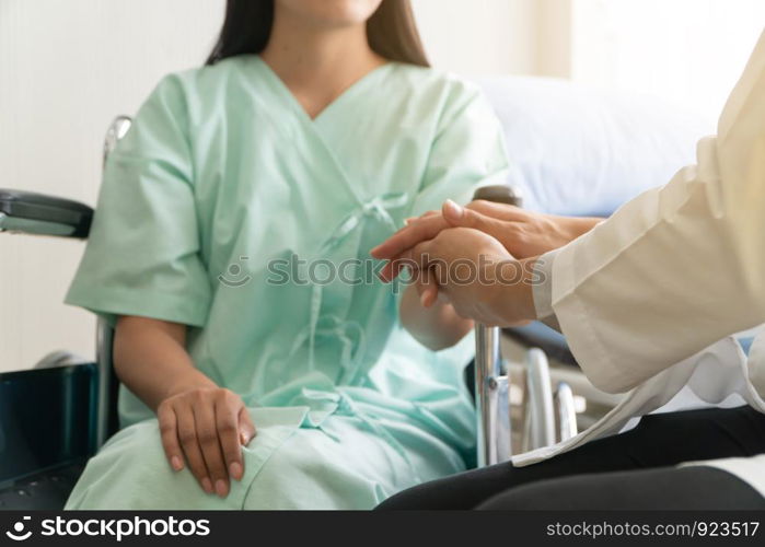 Soft focus and blur of patient sitting in wheelchair in the hospital. And the doctor is holding the patient?s hand to encourage. Concept of healthcare patient lifestyle and medical.