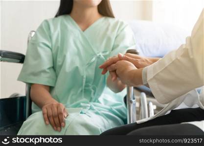 Soft focus and blur of patient sitting in wheelchair in the hospital. And the doctor is holding the patient?s hand to encourage. Concept of healthcare patient lifestyle and medical.