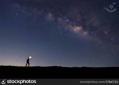 Soft focus climber with fire in the hand on rocky mountain peak, find the target, search under the stars and Milky Way Galaxy at night, success or winner, leader concept. High iso with Noise. . Leader on top.