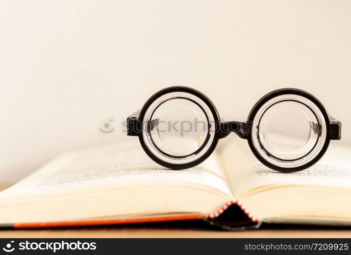 soft focus glasses with blur books stack on wooden desk in university or public library room or book store.concept of knowledge and education.