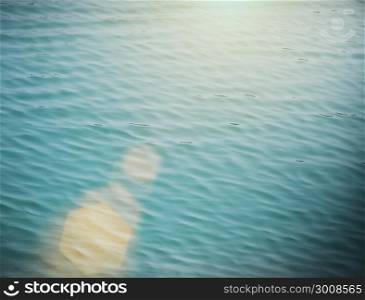 Soft focus of blue water wave with flare. Vintage filtered nature background.