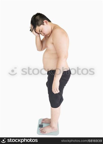 Soft focus of fat boy disappoint his fatness while standing on on weighing machine over white background