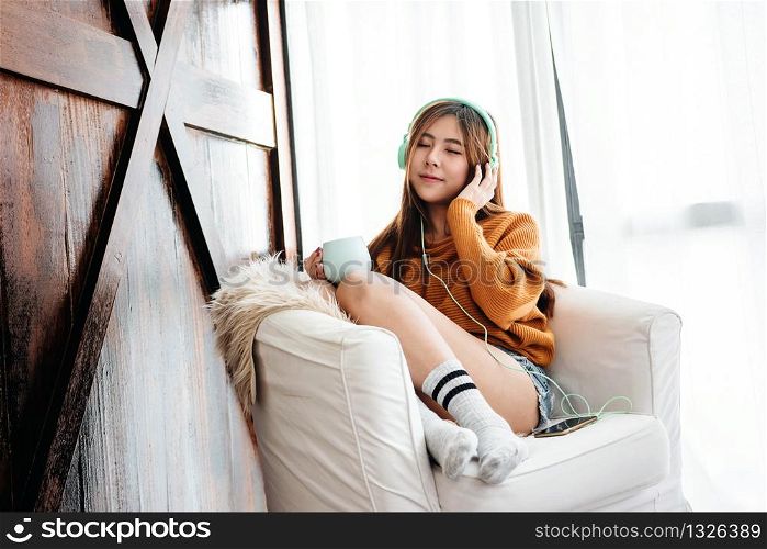 Soft Focus of Happy Young Woman Relaxing by Music Headphone from Smartphone on Sofa in Cozy House, Lifestyle of Modern People