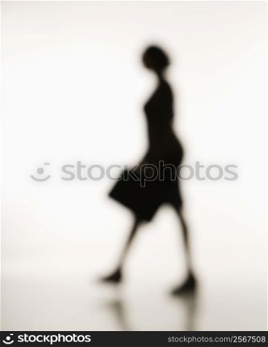 Soft focus silhouette of walking businesswoman holding briefcase.