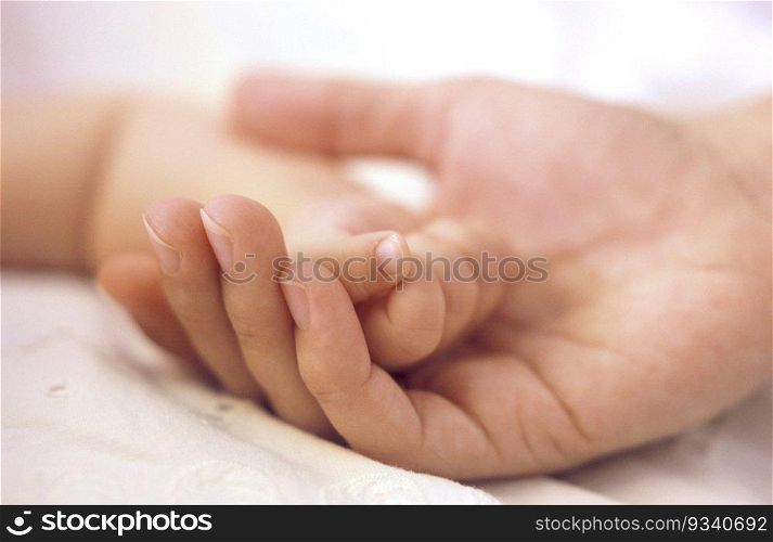 Soft little baby hand in mothers hand close up